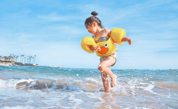 girl playing beside body of water during daytime